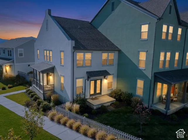 Multi-story exterior with light-toned masonry, double-entry front doors, covered porch, and enclosed side patio