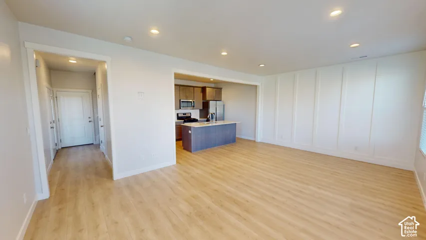 Wood-finish flooring, recessed lighting, board-and-batten wall detailing, and an island kitchen featuring stainless steel appliances
