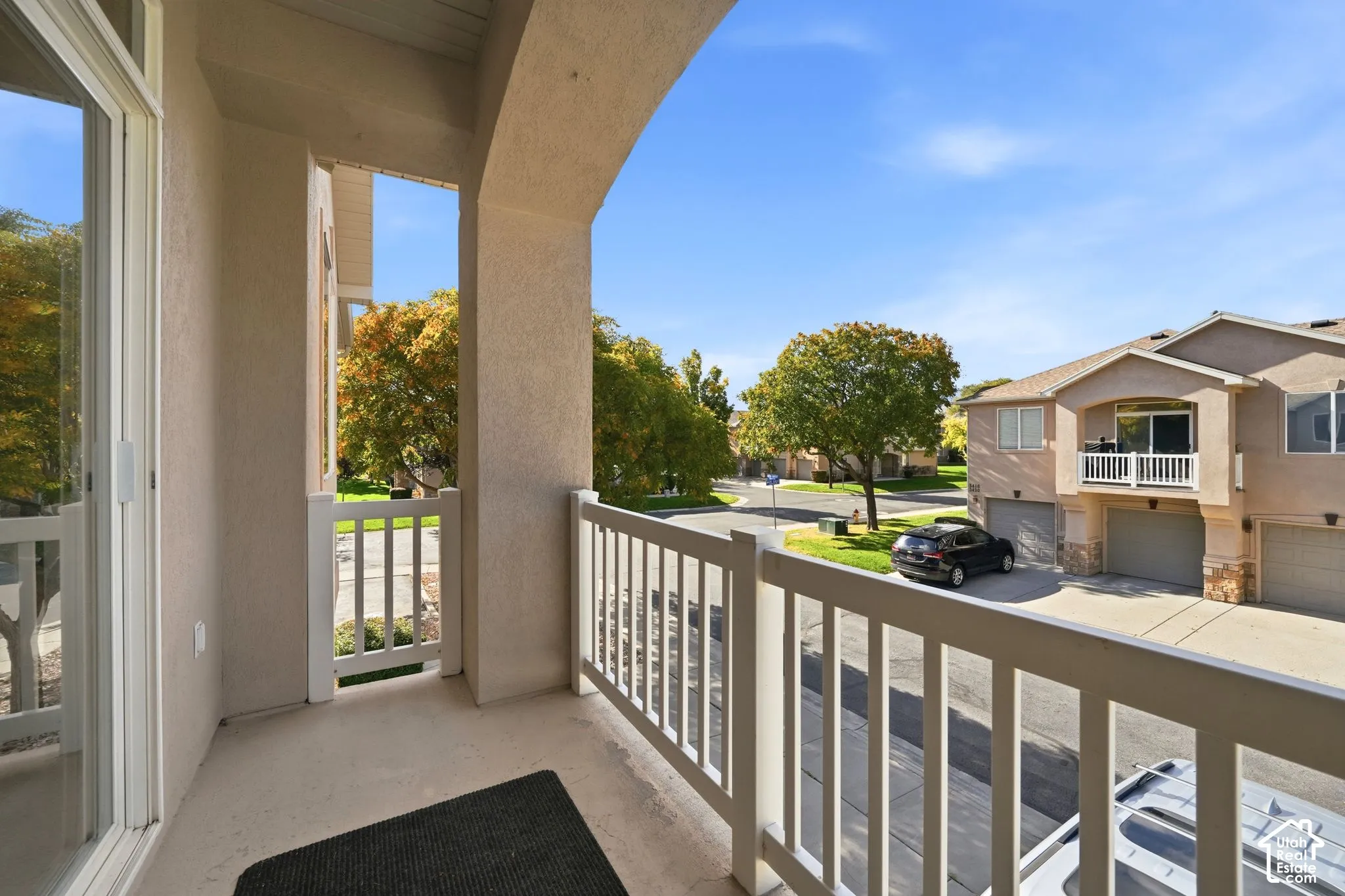 Covered balcony featuring stucco-finished walls, a painted wood railing, and concrete flooring