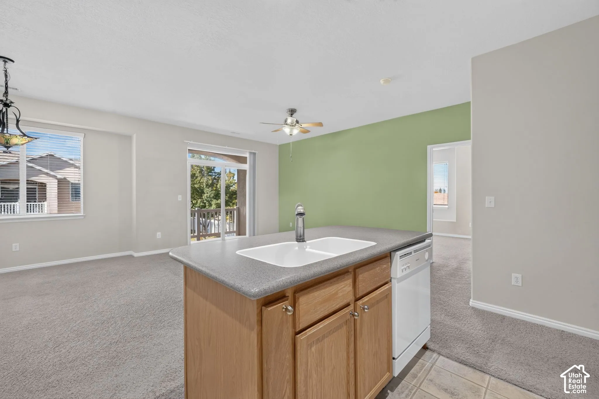 Kitchen island featuring wood cabinetry, a dual-basin sink, a faucet, and a dishwasher, accented by a sliding glass door