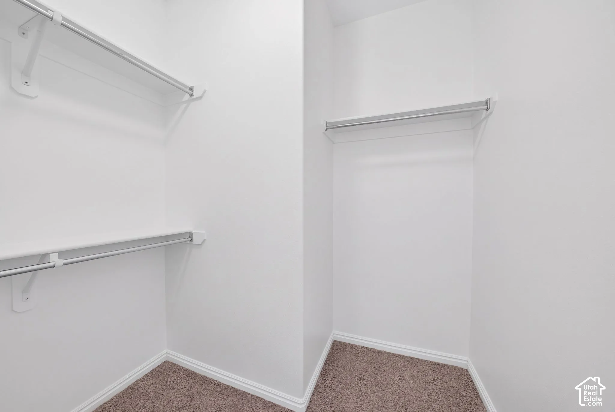 Walk-in closet featuring neutral carpeting, white walls, and multiple levels of built-in metal shelving with integrated clothing rods