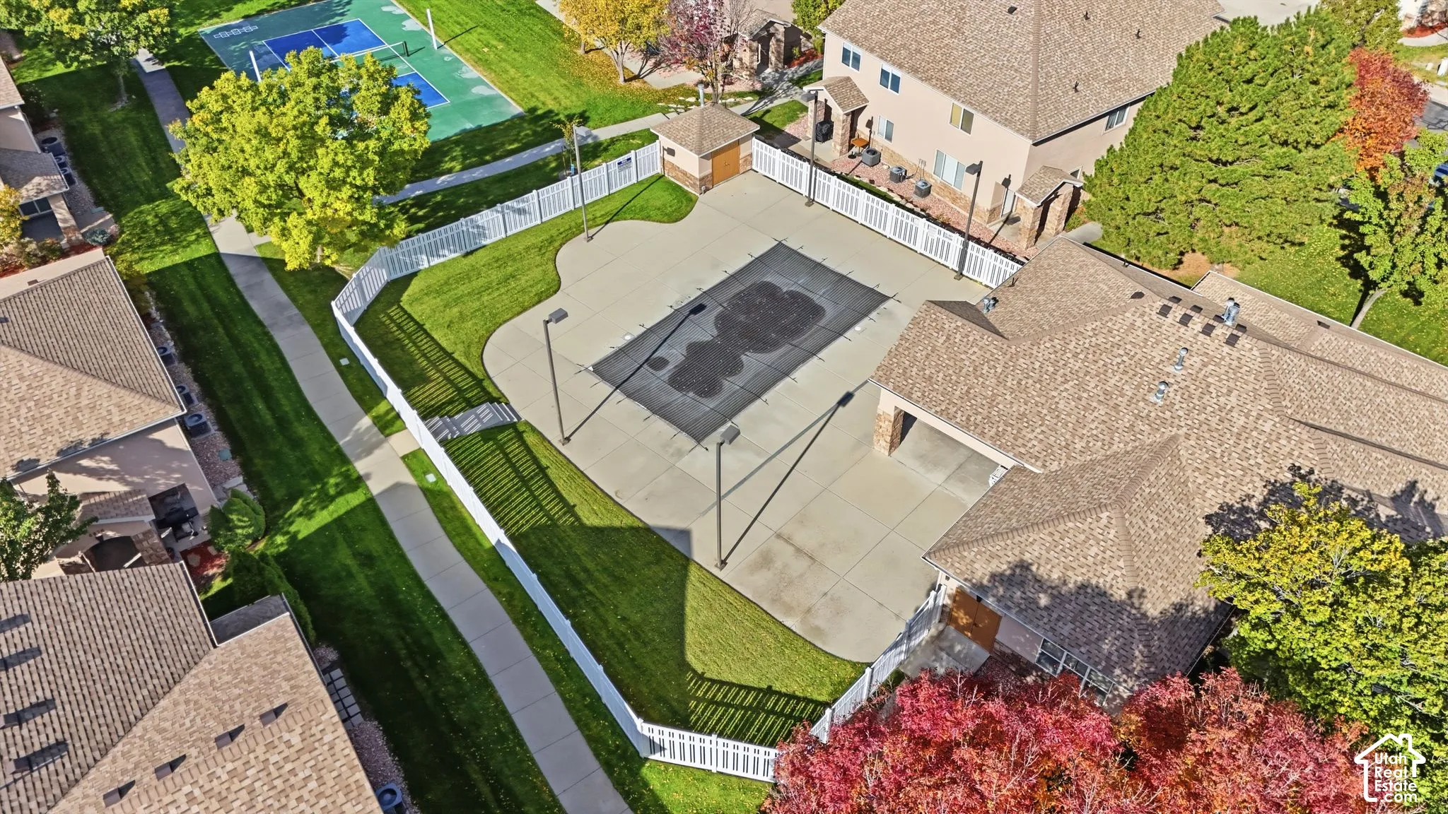 Fenced outdoor space featuring a covered swimming pool, concrete decking, and surrounding lawn