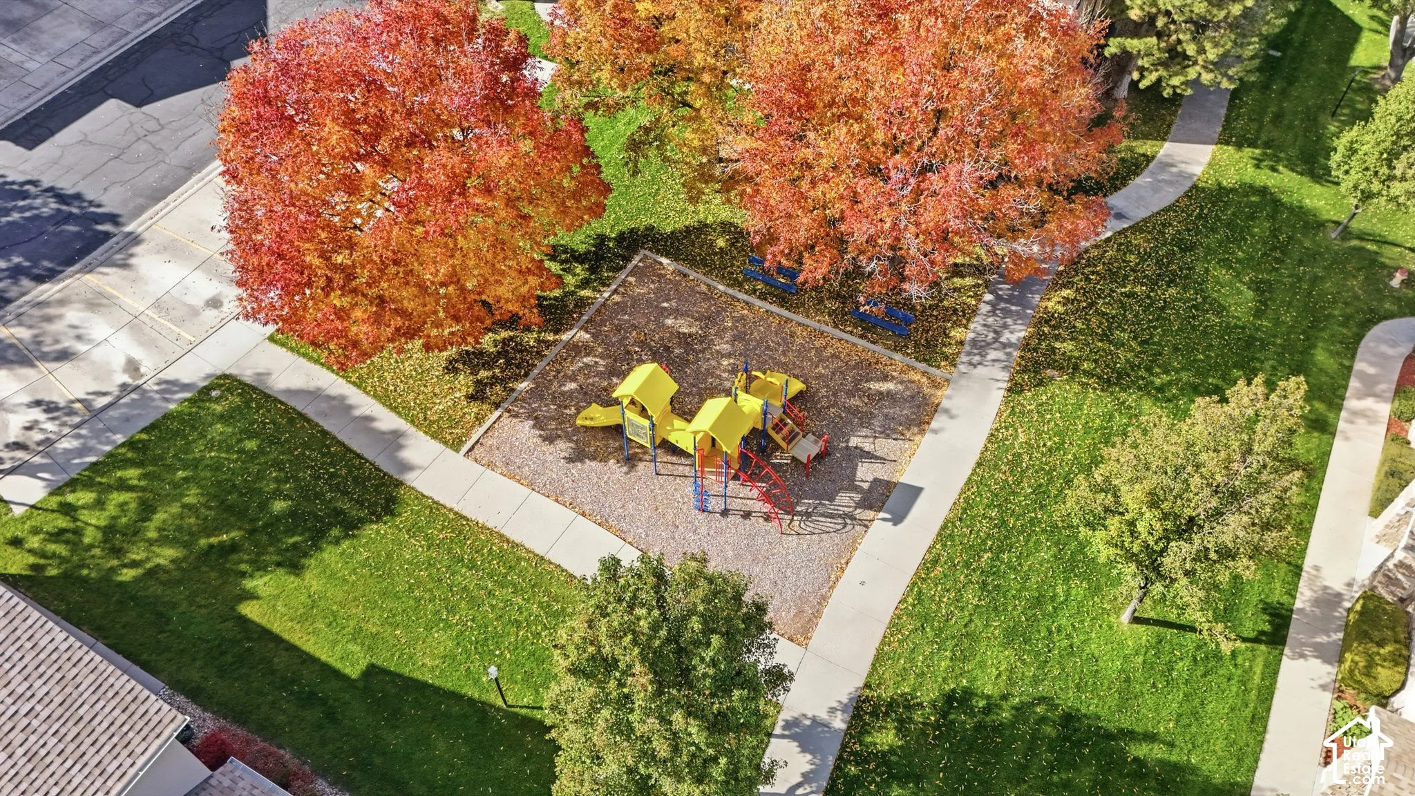 Outdoor area featuring a recreation structure, concrete pathways, manicured lawn, and mature trees