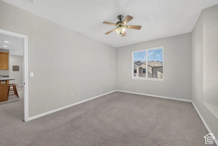 Neutral interior room featuring neutral carpeting, a ceiling-mounted light fixture with a fan, and a single-pane window