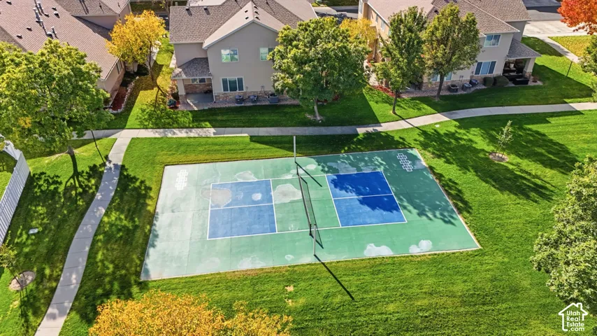 Common area pickleball court featuring a multi-surface court, center net, surrounding turf grounds, and paved walking paths