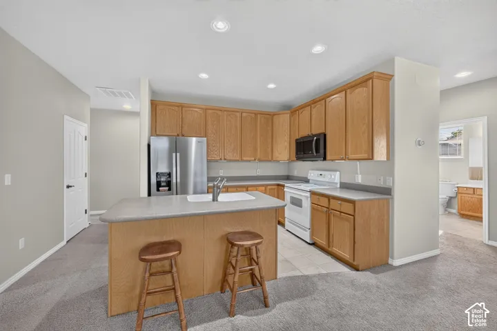 Kitchen featuring wood cabinetry, a central island with a drop-in sink, solid-surface countertops, and recessed lighting