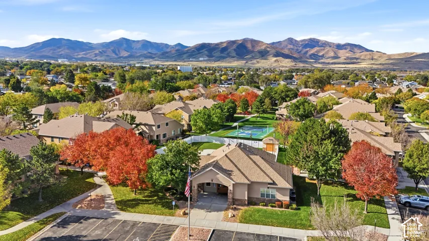 Aerial perspective featuring mountain scenery, multi-pitch roofline architecture, an on-site tennis court, and mature landscaping