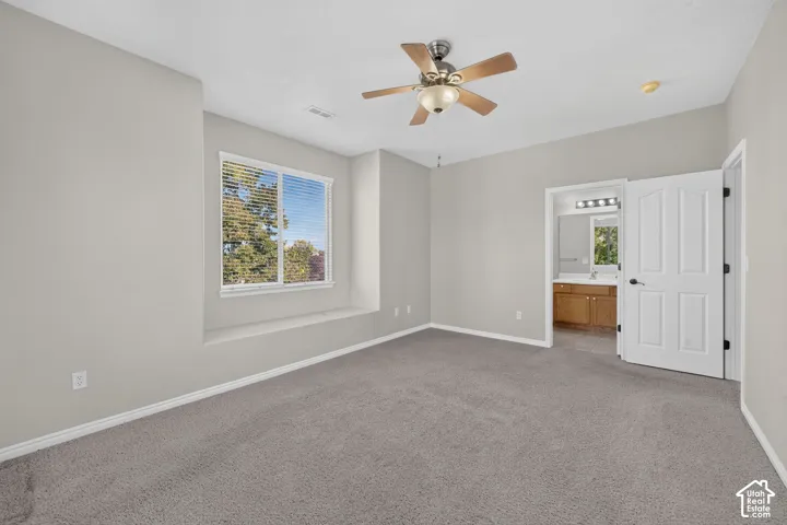Neutral wall palette with plush carpeting, built-in window seat, ceiling fan with integrated light fixture, and arched-panel interior door