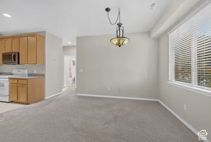 Natural wood-finish cabinetry, built-in microwave, recessed lighting, ornate multi-pane pendant light fixture, and horizontal blind window coverings