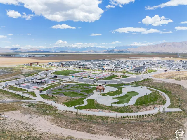 Community park featuring a pump track, concrete skate area, paved walking paths, a gazebo, and mountain backdrop