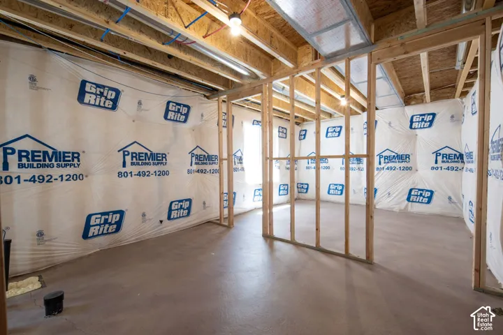 Unfinished interior space featuring exposed wood-stud framing, concrete floor, and moisture-resistant vapor barrier
