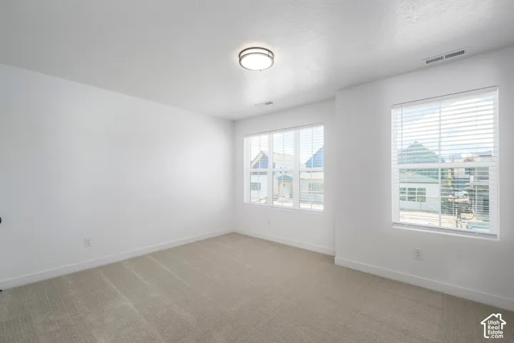 Bedroom #3. Neutral-toned interior featuring wall-to-wall carpeting, multiple windows with blinds, and a circular flush-mount light fixture