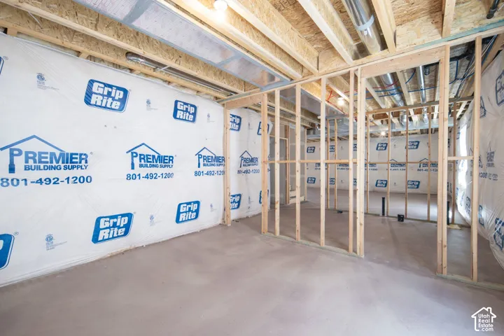 Unfinished space featuring exposed timber framing, concrete flooring, vapor barrier foundation wall covering, and exposed ceiling joists with ventilation ductwork