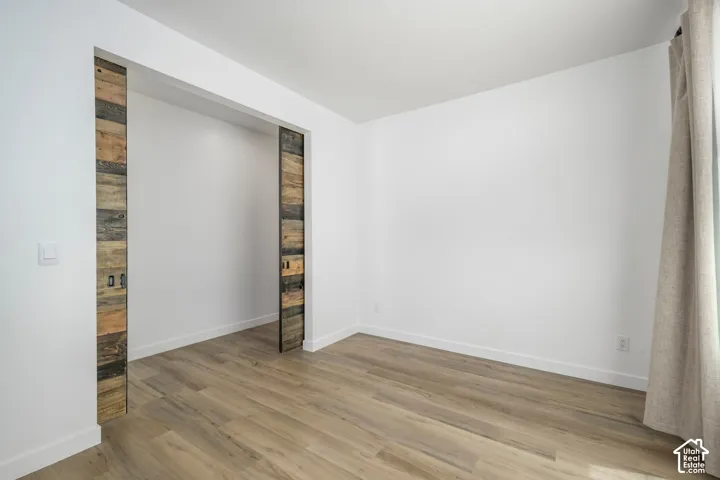 Interior space featuring wood-finish flooring, white walls, and reclaimed wood-style sliding doors