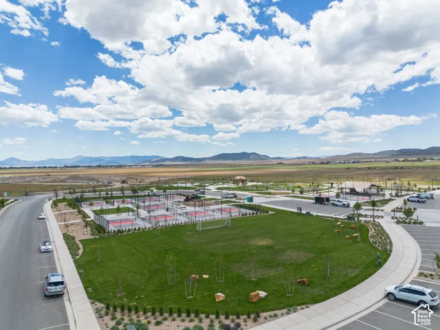 Outdoor recreation space featuring multiple pickleball courts, a grass field, and mountain backdrop