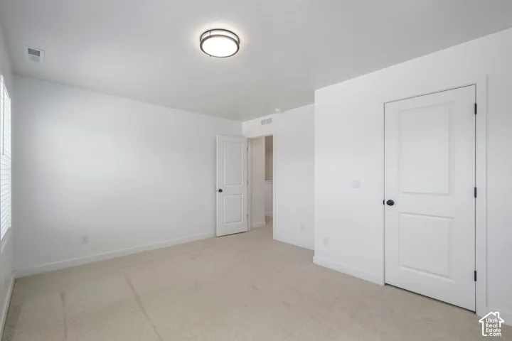 Bedroom #3 with walk in closet. Neutral interior featuring wall-to-wall carpeting, flush-mount circular lighting, and white six-panel interior doors with matte black hardware