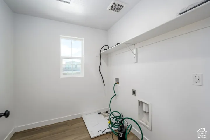 Laundry room featuring wood-finish flooring, a single window, and a built-in wall shelf