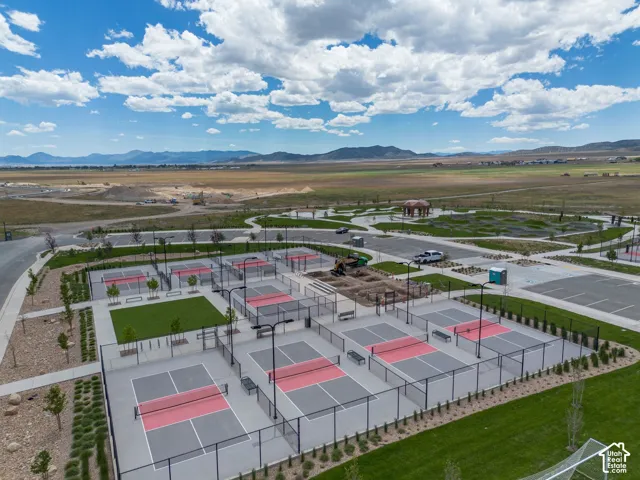 Multi-court outdoor facility featuring dedicated pickleball play surfaces, perimeter fencing, high-mast lighting, and curated landscaping
