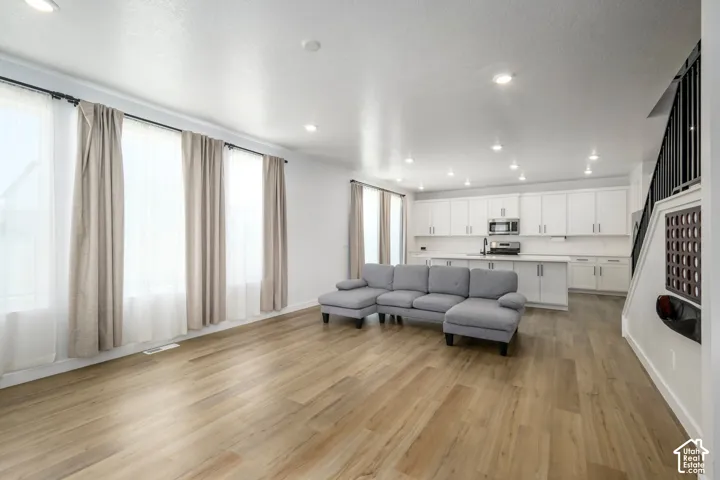 Open-concept interior featuring wood-finish flooring, recessed lighting, and white cabinetry