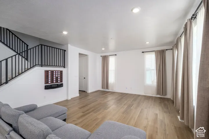 Open-concept interior featuring wood-finish flooring, recessed lighting, and a metal stair railing