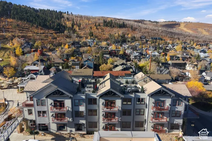 Multi-level architectural exterior featuring board-and-batten siding, metal roofing, stone base detailing, multi-story balconies, and private rooftop terrace space