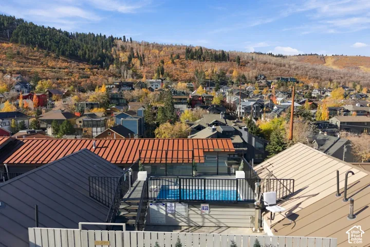 Elevated rooftop swimming pool featuring a metal safety railing, concrete decking, and mountain backdrop