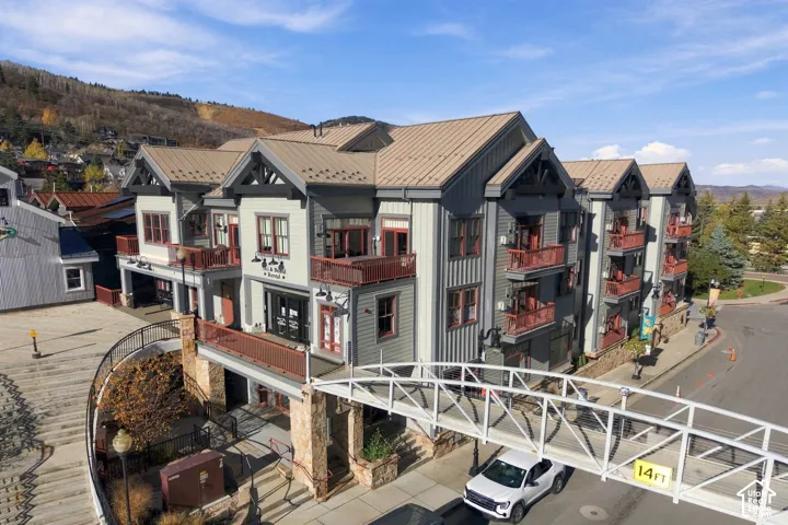 Multi-story structure featuring a standing seam metal roof, vertical siding, stacked stone masonry, and private balconies with metal railings