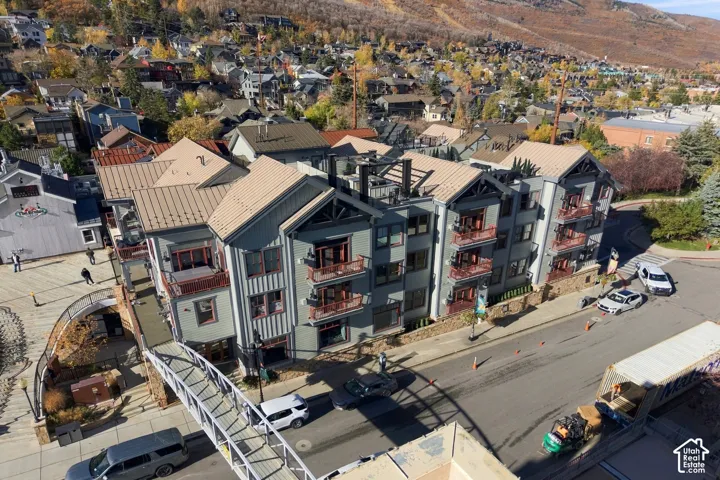Multi-level exterior featuring vertical siding, metal roofing, multiple private balconies with metal railings, and a pedestrian bridge
