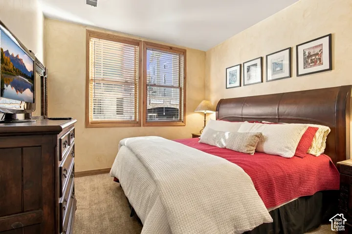 Neutral-toned interior featuring textured wall finishes, carpeted flooring, and dual windows framed in natural wood