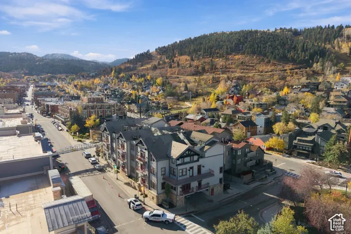 Multi-story exterior featuring a metal roof, stone foundation, dark-toned trim, and private balconies overlooking a mountainous landscape