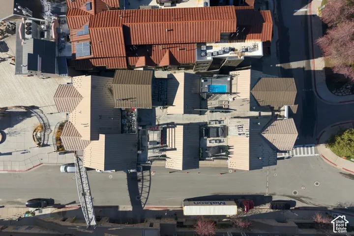 Aerial perspective of a multi-structure property featuring metal roof systems, rooftop pool, and paved surface areas