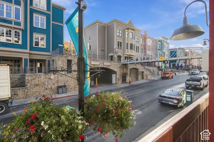 Multi-story architecture with stone masonry facade, covered parking garage entrance, and metal pedestrian bridge
