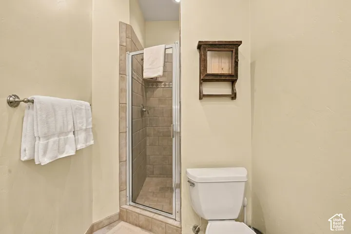 Walk-in shower featuring glass door enclosure, tile surround, and built-in wall-mounted cabinetry