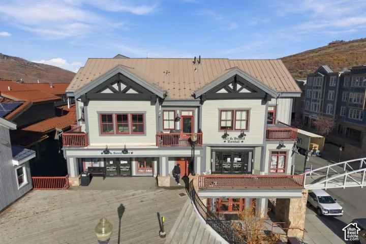 Multi-level structure featuring a metal roof, wood siding, stone accents, decorative timber framing, and multiple exterior balconies
