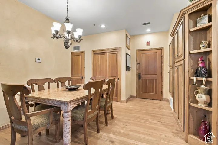 Custom built-in wood cabinetry, wood-finish flooring, solid wood doors, and decorative multi-arm chandelier