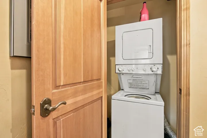 Utility closet featuring a natural wood-finish door with brushed metallic hardware and a stacked laundry appliance unit