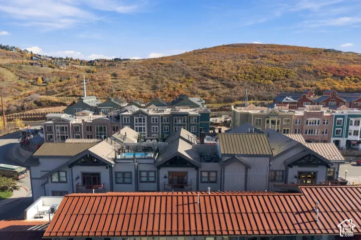 Aerial perspective of multi-story structures featuring standing seam metal roofing, exterior wood siding, balcony railings, and a rooftop pool