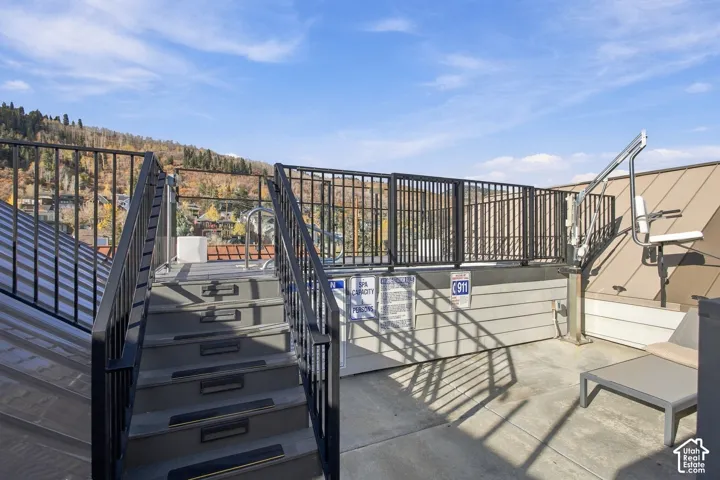 Rooftop terrace featuring a built-in spa, metal railings, exterior stair access, and metallic roofing
