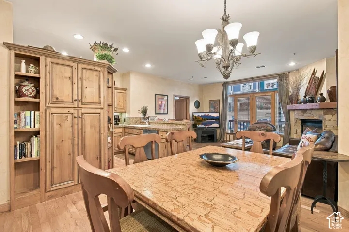 Open-concept interior featuring wood-finish cabinetry, built-in shelving, stone fireplace surround, and decorative multi-light chandelier