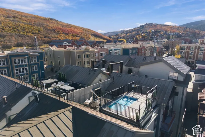 Rooftop terrace featuring a built-in spa, metal perimeter railing, and mountain backdrop