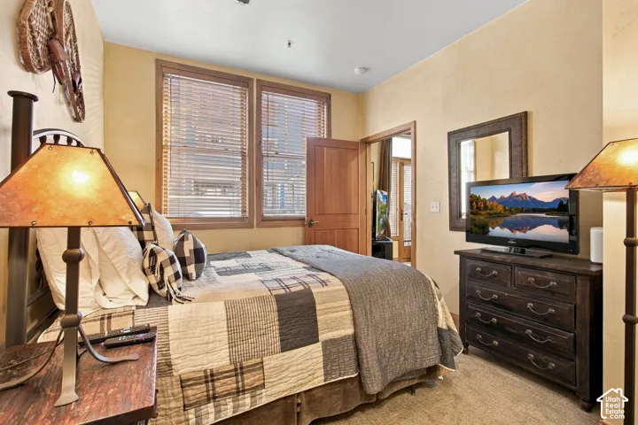 Room featuring textured wall finish, dual windows with wood-tone blinds, solid wood door, and carpeted flooring