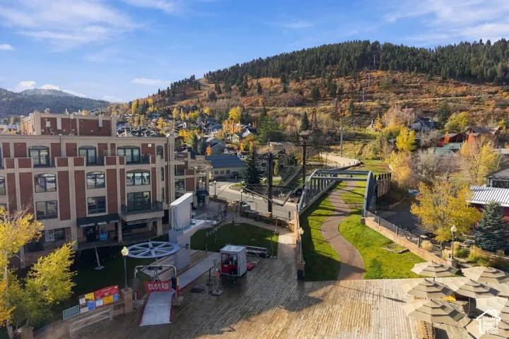 Exterior architecture featuring multi-story brick facade, paved pedestrian walkway, manicured green space, and mountain backdrop