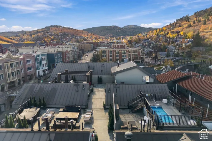 Rooftop terrace featuring concrete hardscaping, a built-in swimming pool with a glass railing, and panoramic mountain backdrop