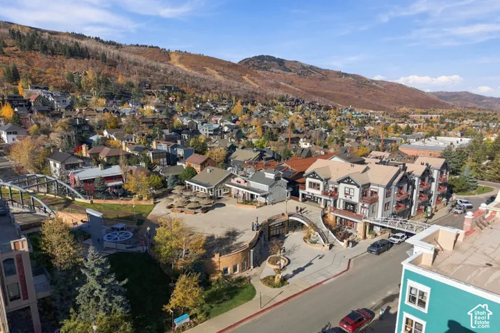 Aerial perspective of a multi-story mixed-use development featuring stone and siding exteriors, metal roofing, terraced balconies, pedestrian walkways, and integrated plaza space
