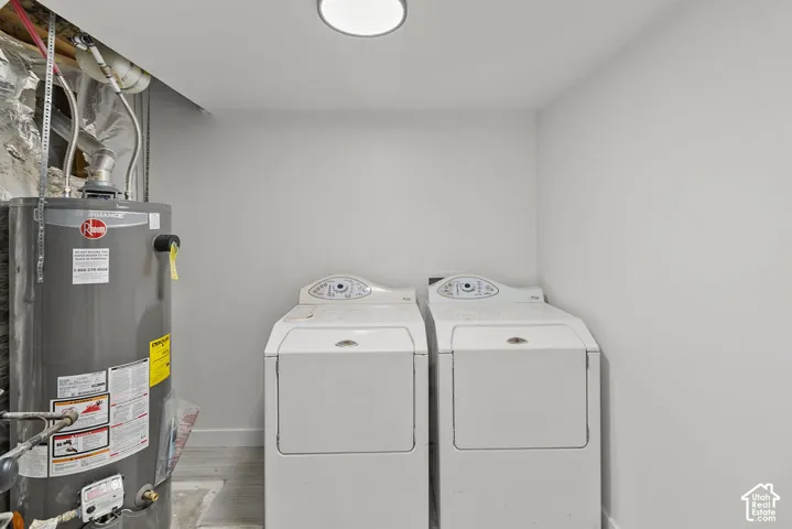 Utility space featuring a water heater and integrated laundry hookups with neutral wall finishes and light-tone flooring