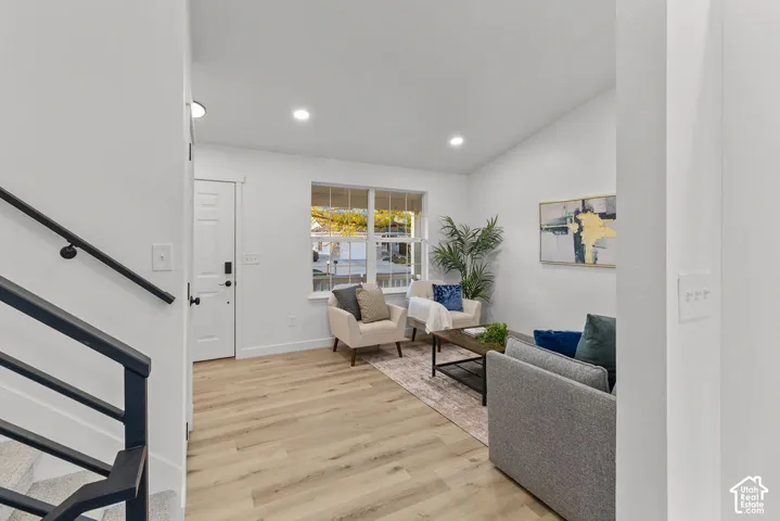 Interior space featuring light wood-finish flooring, recessed lighting, vaulted ceiling, and metal staircase railing