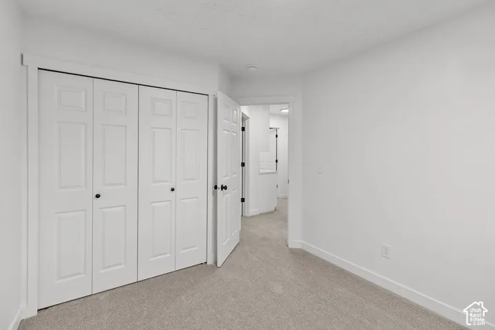 Neutral-toned carpeted flooring, white interior walls, and a multi-panel bi-fold closet door with matte black hardware