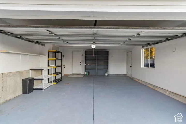 Multi-car garage featuring a sealed concrete floor, dual entry doors, built-in wall shelving, and a window