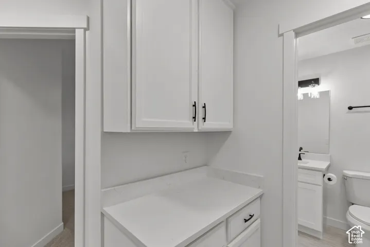 Built-in cabinetry featuring white shaker-style doors, quartz countertops, matte black hardware, and light-tone wood-finish flooring