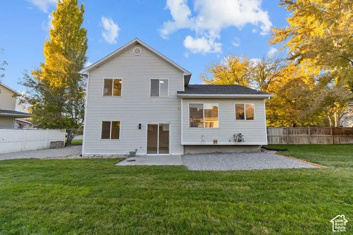 Two-story exterior featuring horizontal siding, a gabled roofline, sliding glass patio doors, a concrete patio, and a fenced backyard